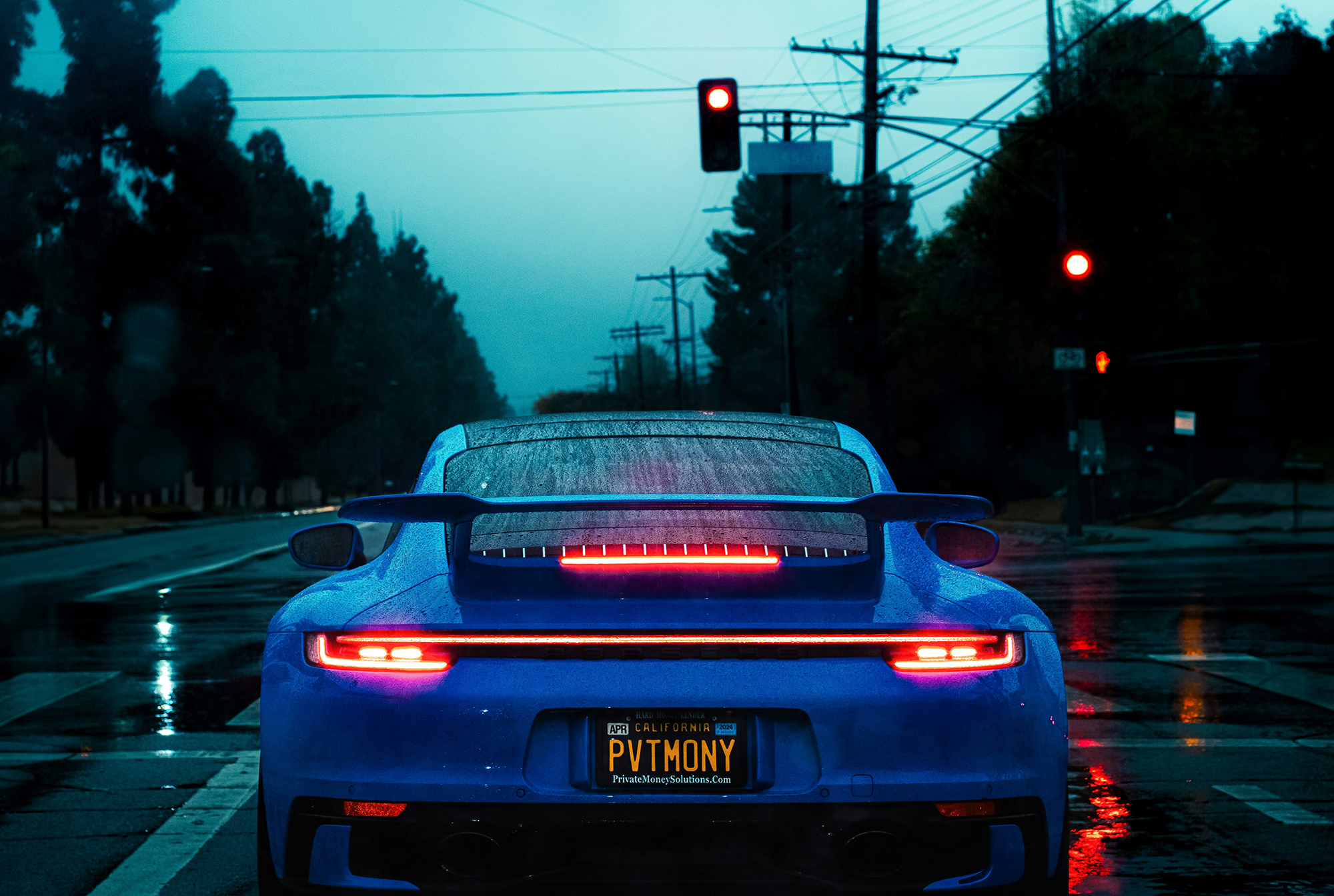 picture took behind a blue modified porsche 911, stopping at a red light intersection